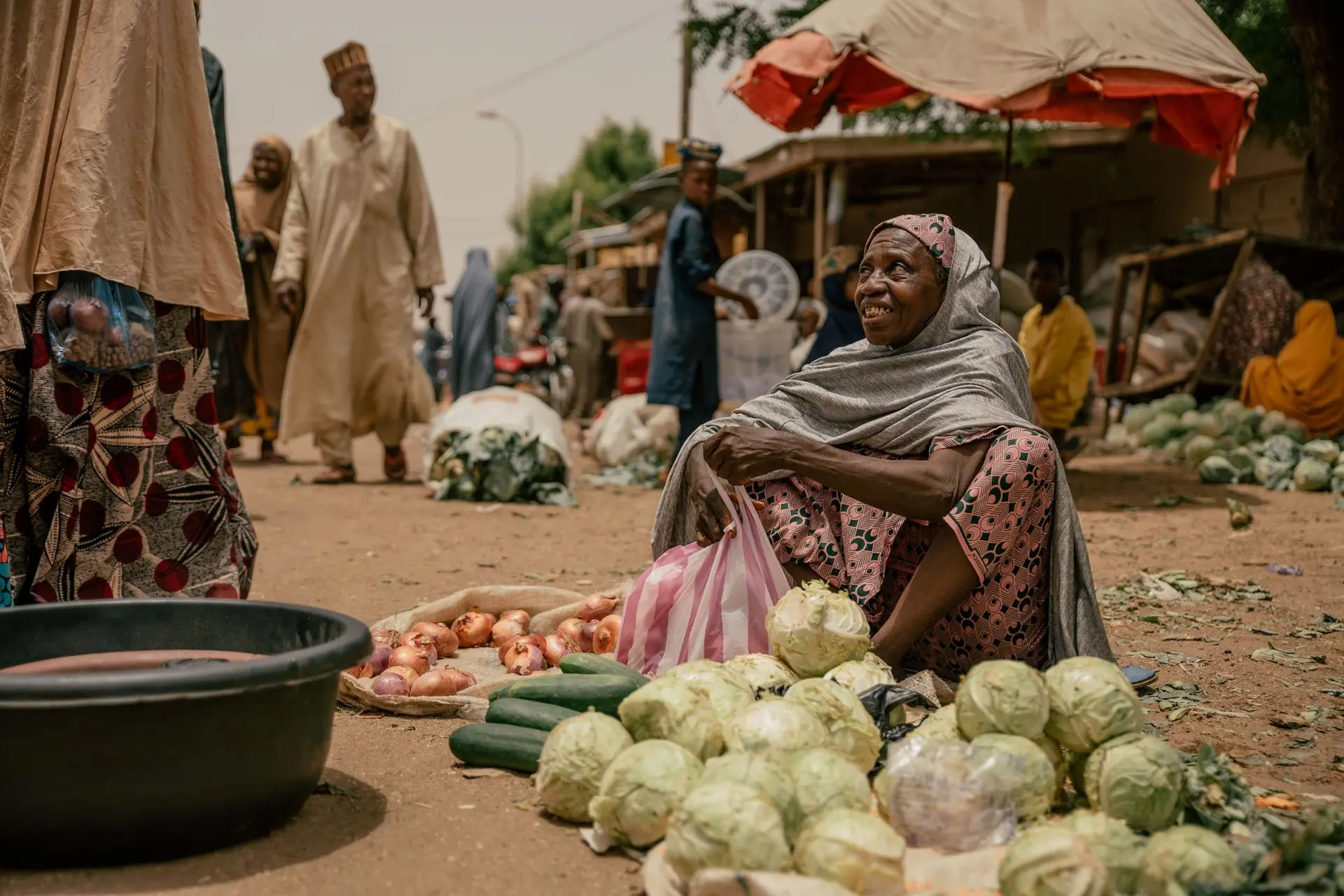 Smiling woman selling fresh vegetables at a West African market